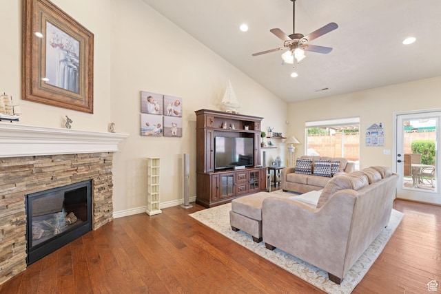 living area with a fireplace, wood finished floors, ceiling fan, and plenty of natural light