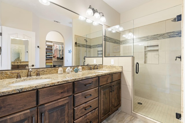 bathroom with a shower stall, a walk in closet, a sink, and visible vents