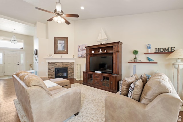 living area featuring recessed lighting, wood finished floors, a ceiling fan, and a stone fireplace