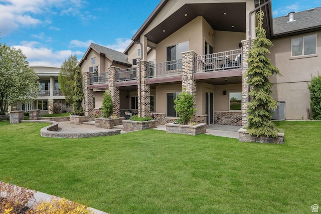 back of property featuring a lawn, a balcony, and stucco siding