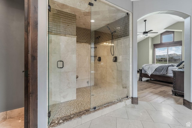 ensuite bathroom with a shower stall, a ceiling fan, ensuite bathroom, tile patterned floors, and lofted ceiling