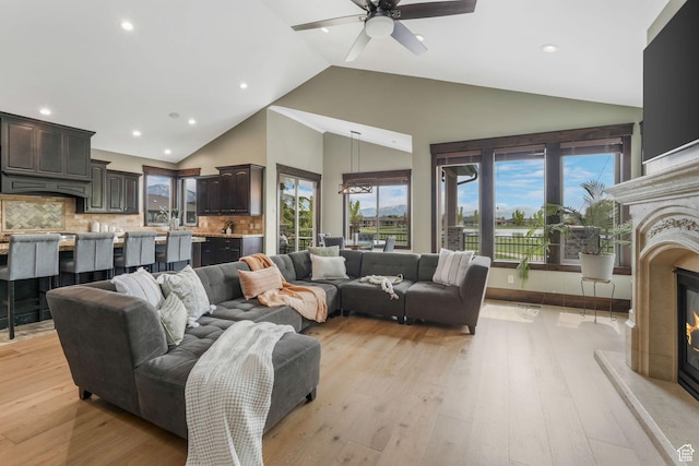 living room featuring recessed lighting, light wood-style floors, a fireplace, high vaulted ceiling, and ceiling fan