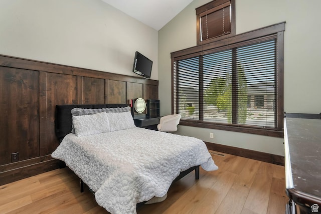 bedroom with lofted ceiling, light wood-style floors, visible vents, and baseboards