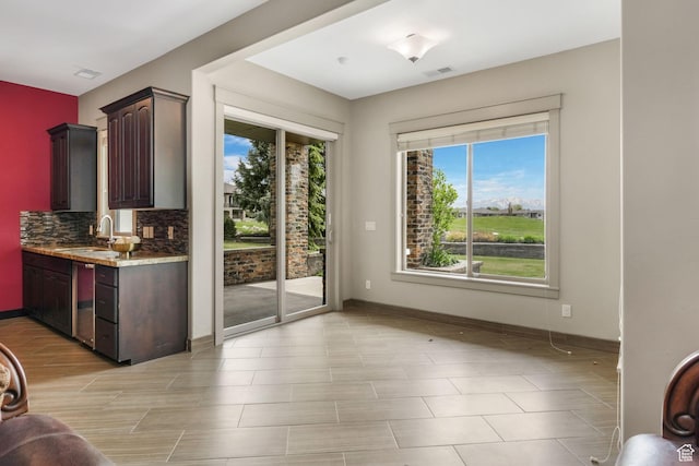 doorway to outside with baseboards, visible vents, and a sink