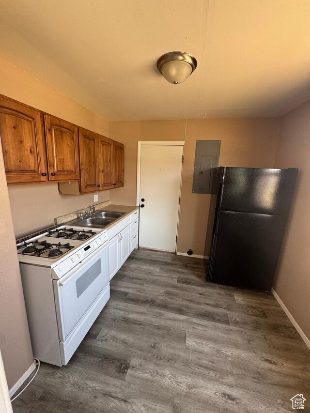 150 Berkley Ave, East Carbon, UT 84520 - kitchen with white gas range, freestanding refrigerator, electric panel, brown cabinets, and dark wood-type flooring
