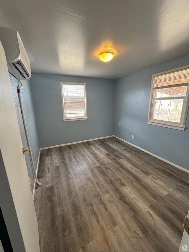 150 Berkley Ave, East Carbon, UT 84520 - empty room with plenty of natural light, baseboards, wood finished floors, and an AC wall unit