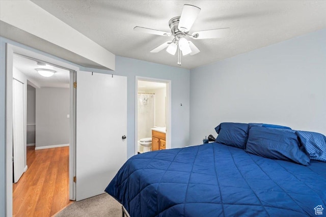 bedroom featuring ensuite bathroom, wood finished floors, and a ceiling fan