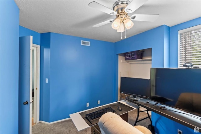 carpeted office space with baseboards, visible vents, and ceiling fan