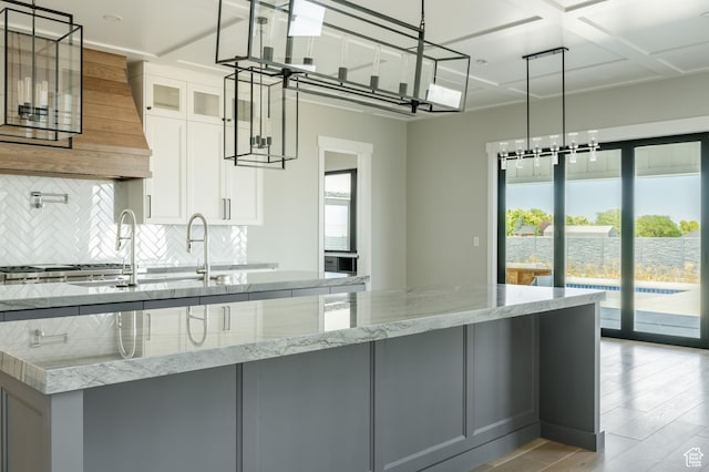 3640 W Kenna Ln Unit 101, Bluffdale, UT 84065 - kitchen featuring backsplash, light wood-style floors, light stone countertops, a center island with sink, and gray cabinetry