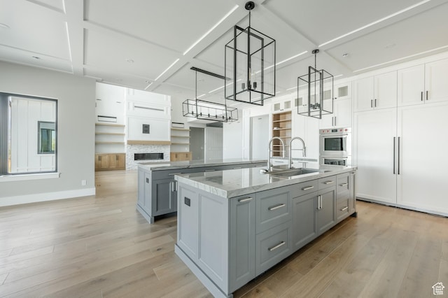 3640 W Kenna Ln Unit 101, Bluffdale, UT 84065 - kitchen with a kitchen island with sink, light wood-style flooring, a sink, baseboards, and gray cabinetry