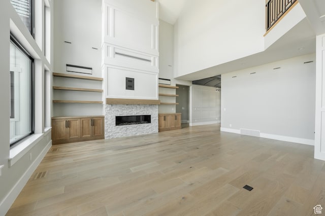 3640 W Kenna Ln Unit 101, Bluffdale, UT 84065 - unfurnished living room with visible vents, a high ceiling, and light wood-type flooring