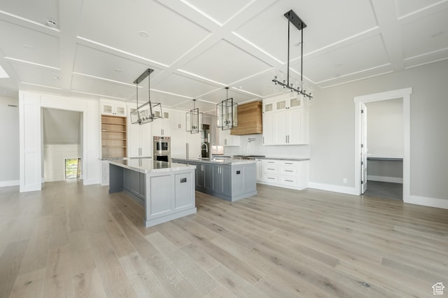 3640 W Kenna Ln Unit 101, Bluffdale, UT 84065 - kitchen with a sink, a kitchen island with sink, light wood-type flooring, baseboards, and coffered ceiling