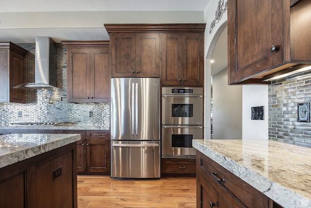 1621 S 4800 E, Heber City, UT 84032 - kitchen featuring stainless steel appliances, wall chimney exhaust hood, backsplash, light stone countertops, and light wood-type flooring
