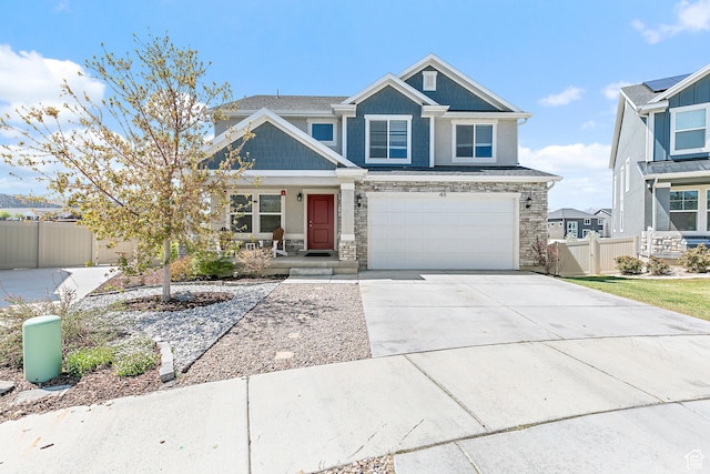 craftsman house with concrete driveway, fence, stone siding, and covered porch