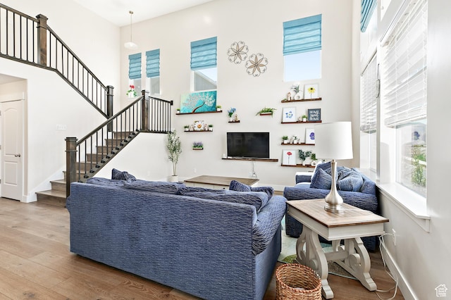 living room with stairway, a high ceiling, wood finished floors, and baseboards