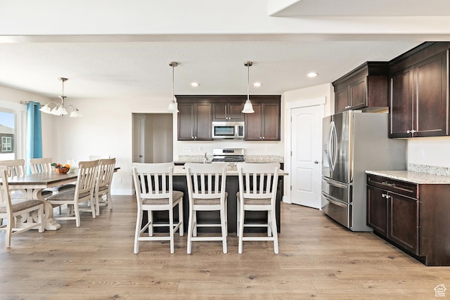 kitchen with light wood-type flooring, dark brown cabinetry, stainless steel appliances, a notable chandelier, and recessed lighting