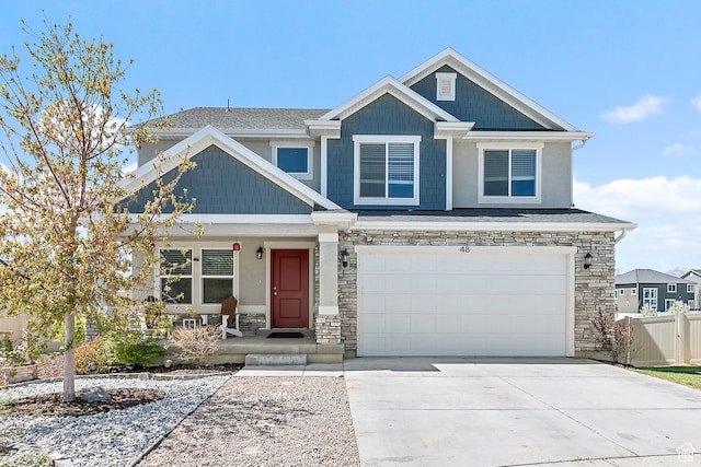 craftsman-style house with fence, concrete driveway, covered porch, stone siding, and a garage