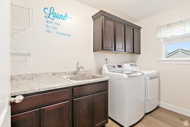 washroom with light wood finished floors, washer and clothes dryer, a sink, baseboards, and cabinet space
