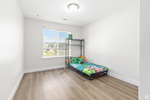 bedroom featuring baseboards, wood finished floors, and visible vents