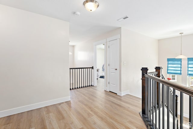 hall featuring baseboards, light wood finished floors, an upstairs landing, and visible vents