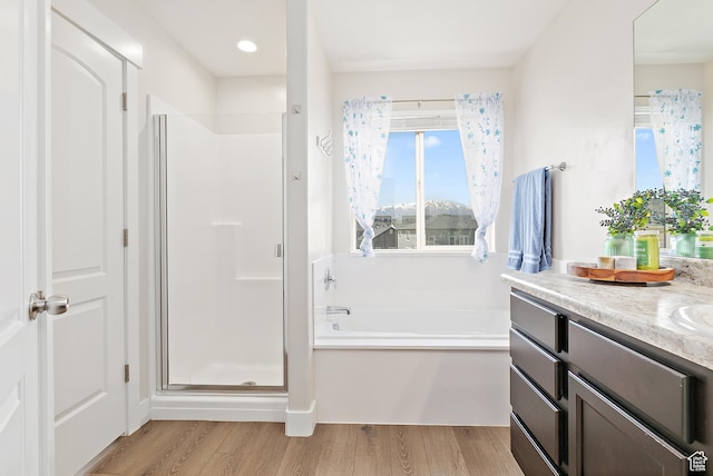 full bathroom featuring a bath, vanity, wood finished floors, and a stall shower