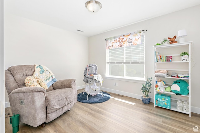 living area featuring baseboards, wood finished floors, and visible vents