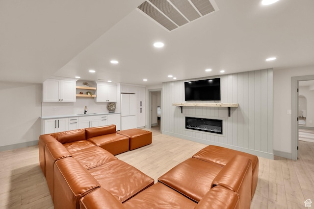 living area featuring light wood-style flooring, wet bar, baseboards, visible vents, and recessed lighting