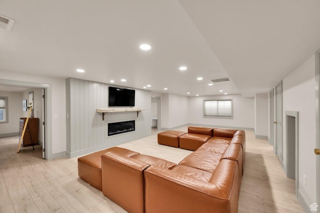 living room with a fireplace, visible vents, and light wood-type flooring