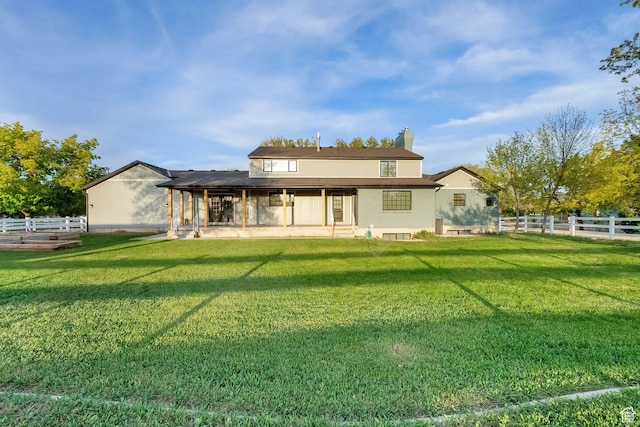 rear view of house with fence, a chimney, a yard, and a patio