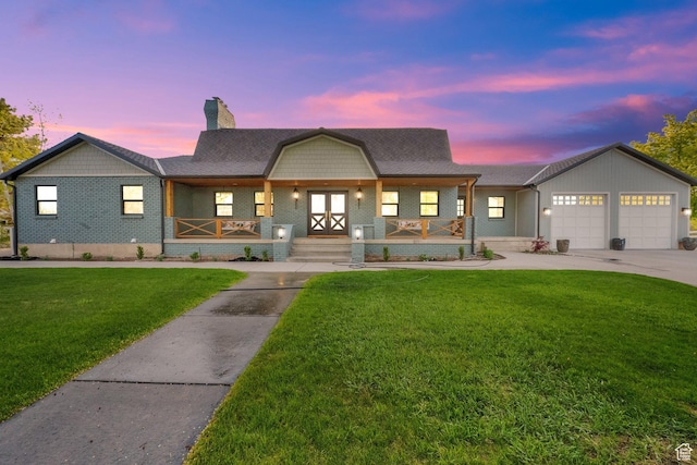 view of front of home with a chimney, driveway, covered porch, an attached garage, and a front yard