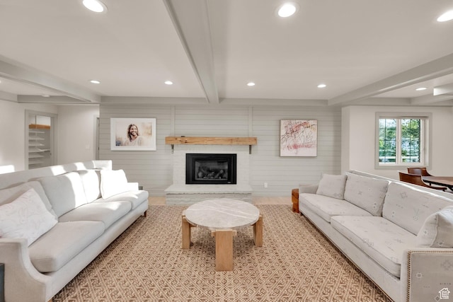 living area featuring a glass covered fireplace, beamed ceiling, and recessed lighting