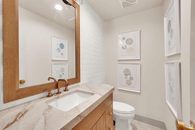 bathroom with baseboards, visible vents, vanity, and toilet