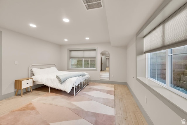 bedroom featuring light wood-style floors, arched walkways, and recessed lighting