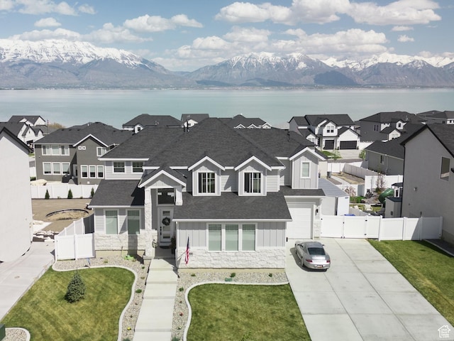 view of front of home featuring board and batten siding, driveway, a water and mountain view, and stone siding