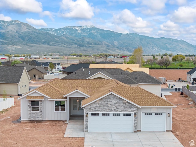 view of front facade with driveway, board and batten siding, a shingled roof, a mountain view, and a garage