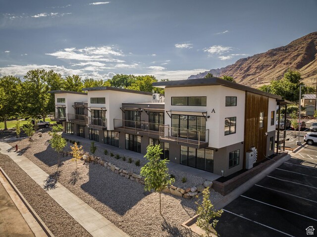 443 W Kane Creek Blvd Unit A206, Moab, UT 84532 - rear view of house with stucco siding, uncovered parking, a balcony, and a mountain view