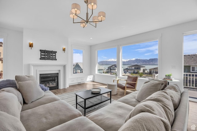 2948 S Puddle Ln, Saratoga Springs, UT 84045 - living area with a chandelier, a glass covered fireplace, a mountain view, and wood finished floors