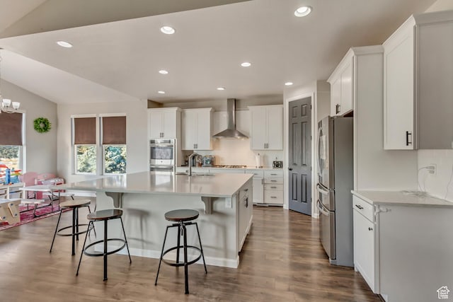 kitchen featuring wall chimney exhaust hood, stainless steel appliances, a breakfast bar, and a sink