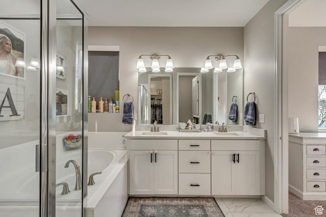 full bath with a garden tub, marble finish floor, a sink, and double vanity