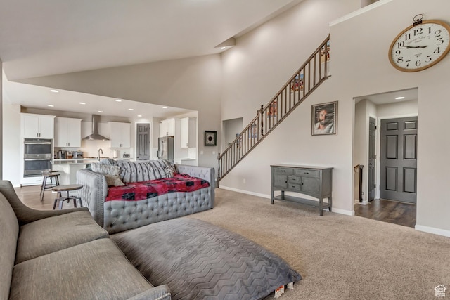 living area featuring baseboards, stairs, carpet flooring, and high vaulted ceiling