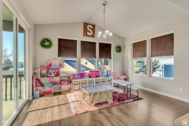 interior space with an inviting chandelier, vaulted ceiling, wood finished floors, and a wealth of natural light
