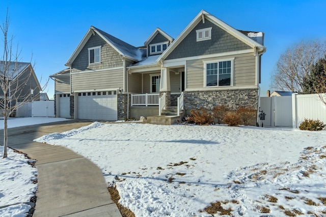 craftsman-style house with a gate, fence, an attached garage, a porch, and stone siding