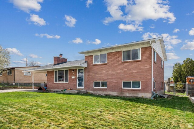 374 S Fairlane, Tooele, UT 84074 - view of front of property featuring fence, a chimney, brick siding, and a front yard