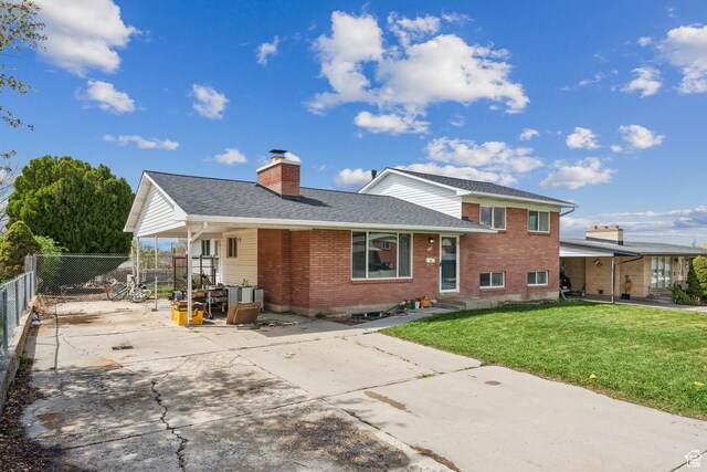 374 S Fairlane, Tooele, UT 84074 - back of property featuring a lawn, a chimney, concrete driveway, fence, and brick siding