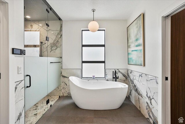 655 Wilard Peak Rd, Mantua, UT 84324 - bathroom featuring tile walls, wainscoting, a marble finish shower, and a freestanding bath