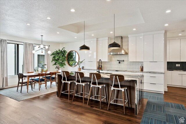 655 Wilard Peak Rd, Mantua, UT 84324 - kitchen with dark wood finished floors, a kitchen bar, modern cabinets, decorative backsplash, and wall chimney range hood