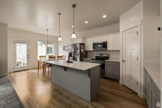 269 W 590 N, Vineyard, UT 84059 - kitchen with dark wood-style floors, stainless steel appliances, a breakfast bar, a sink, and a kitchen island with sink