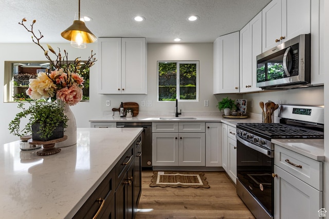 kitchen with a sink, light wood-style floors, stainless steel appliances, white cabinetry, and recessed lighting