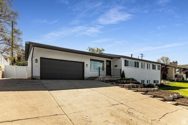 view of front of property with a garage, brick siding, concrete driveway, and fence