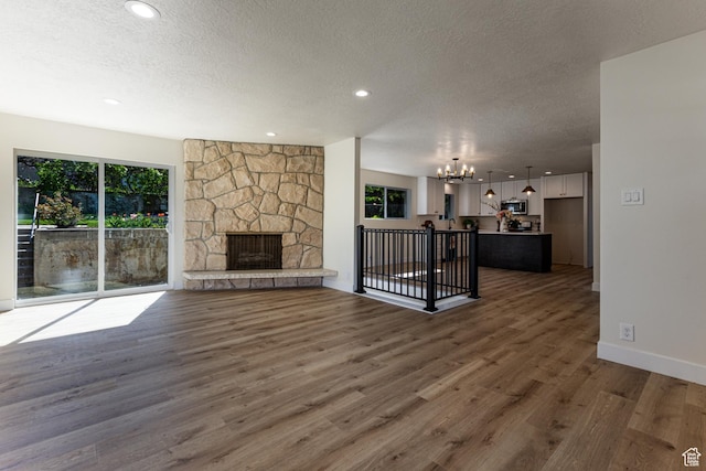 unfurnished living room with a chandelier, wood finished floors, a textured ceiling, and recessed lighting